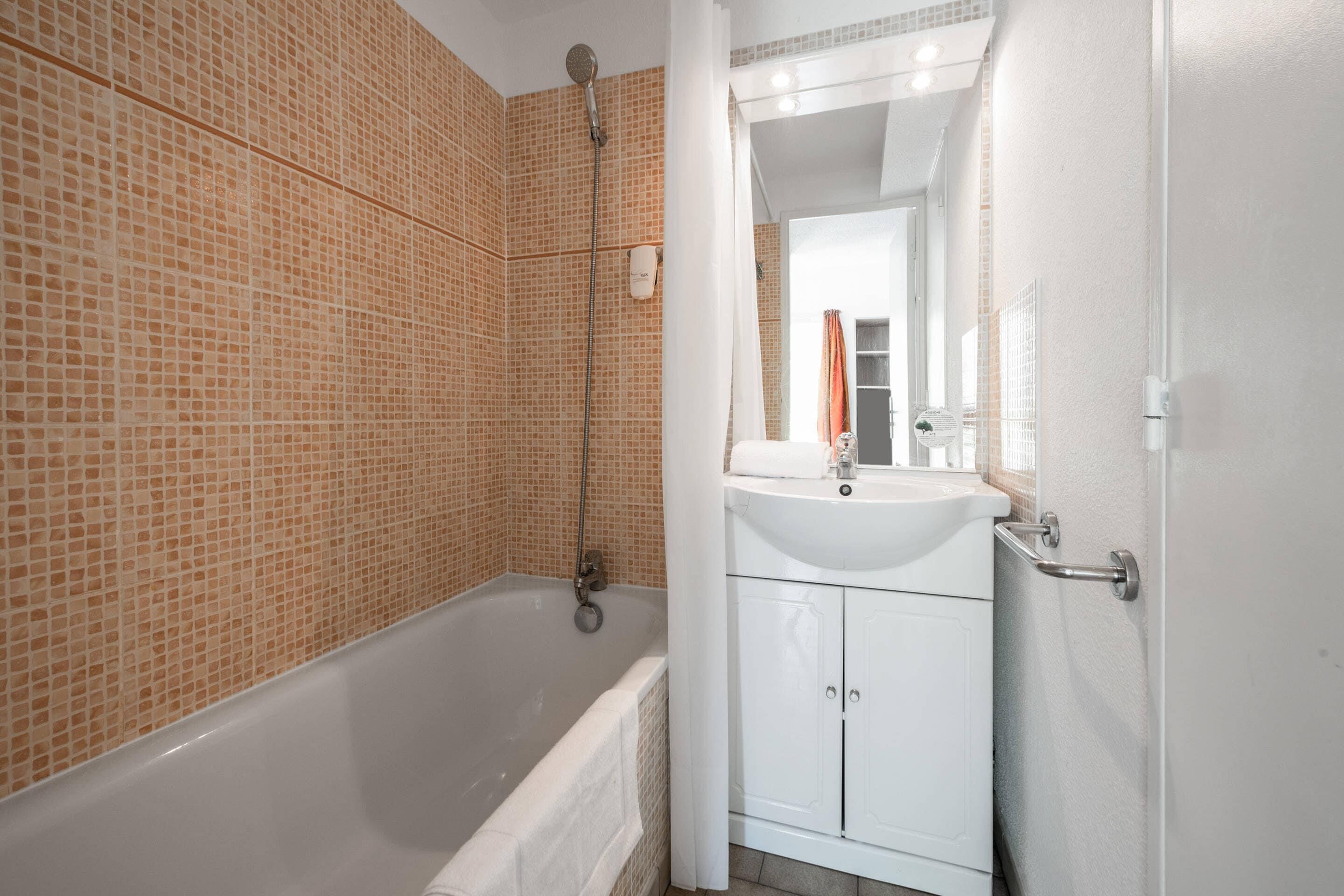 A bathroom with a bathtub, a sink, and a mirror.