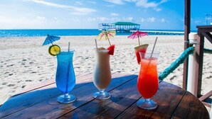 Three drinks on a wooden table with a beach view. - La Ensenada Beach Resort - All Inclusive (Tela)