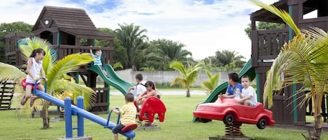 A playground with seesaws, a slide, and a red toy car.