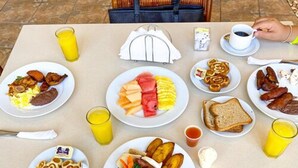 A breakfast table with various dishes, drinks, and a handbag. - La Ensenada Beach Resort - All Inclusive (Tela)