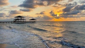 Na praia, areia branca, espreguiçadeiras, guarda-sóis