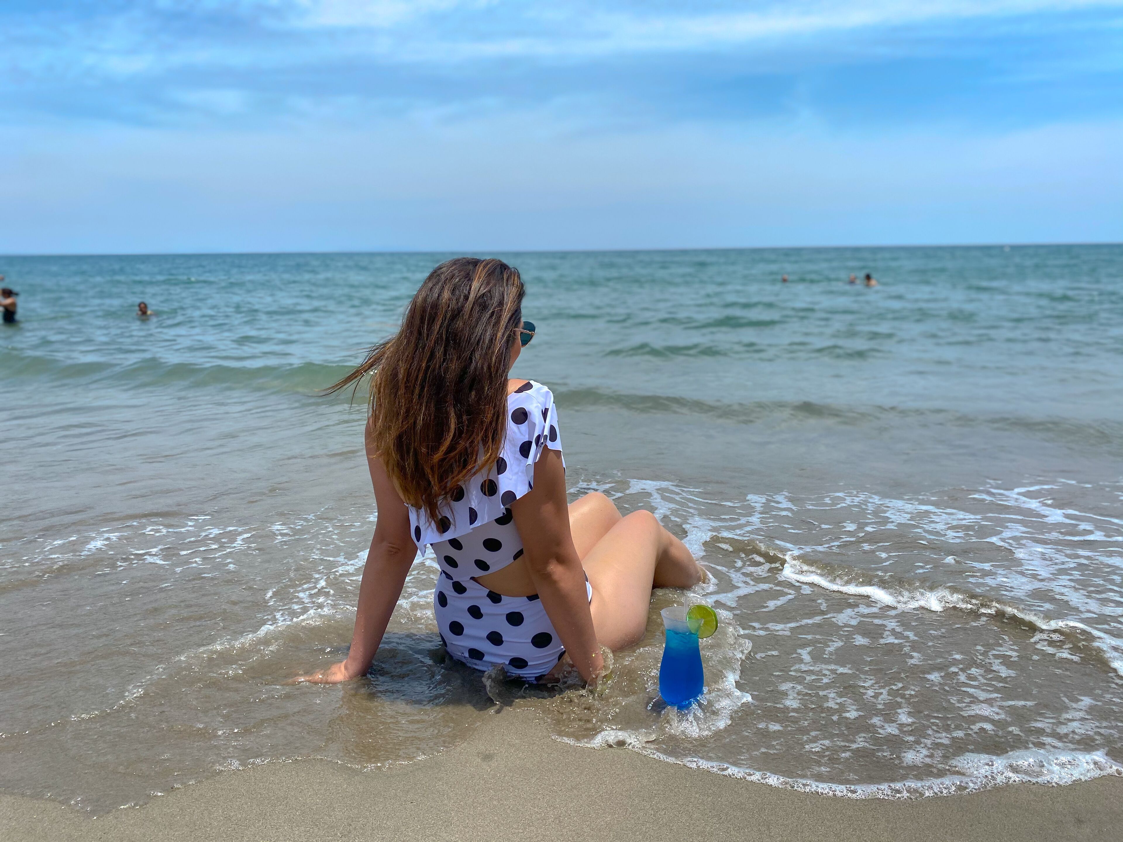 A person sitting on the beach with a drink and a lime.