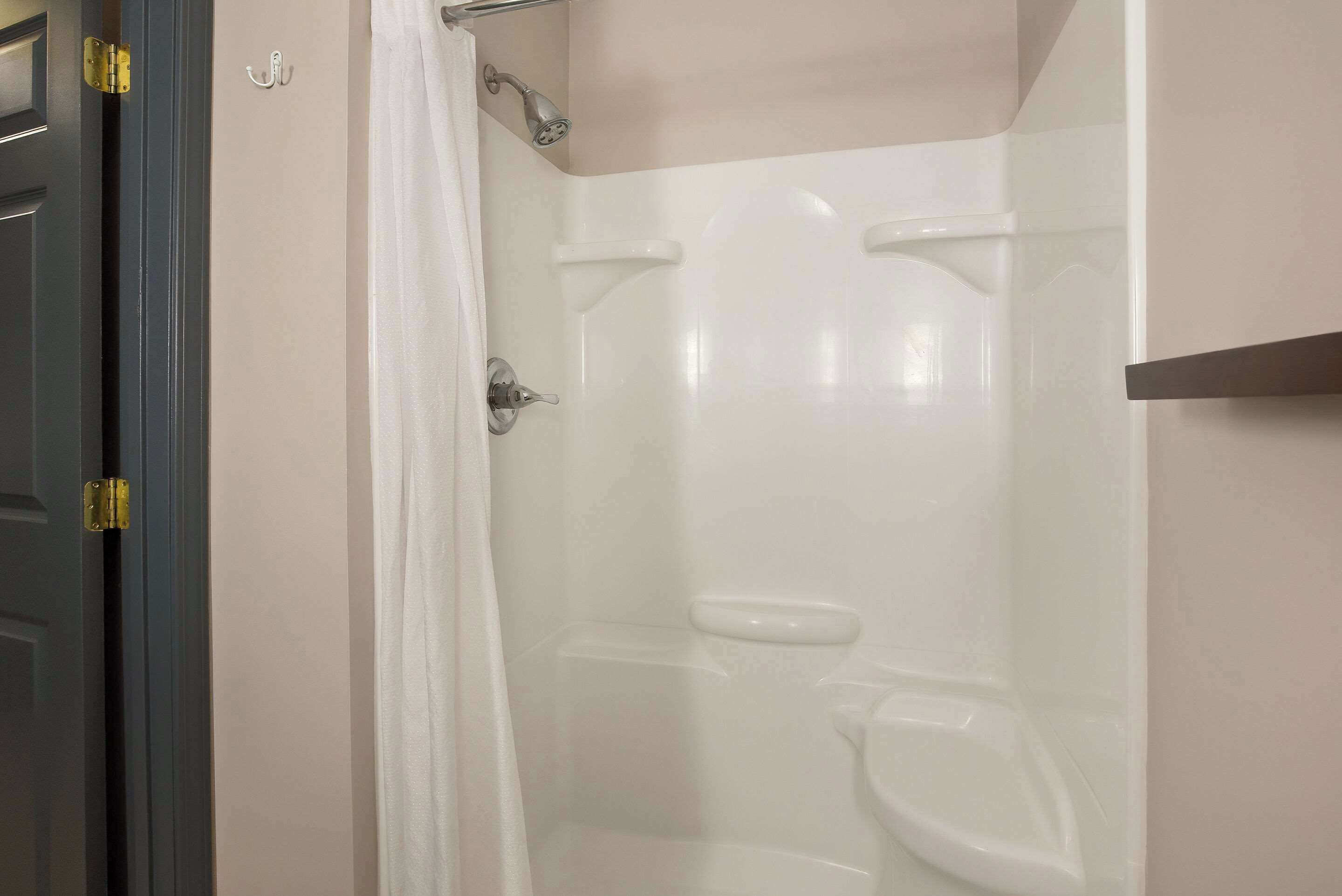 Een badkamer met een douchecabine van glas, een toilet en een deur met een gouden handgreep.