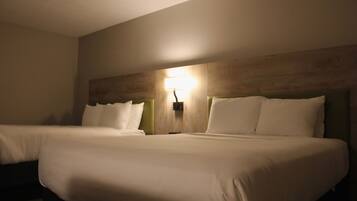 Ett hotellrum med två sängar, en sänggavel i trä och en väggmonterad lampa.