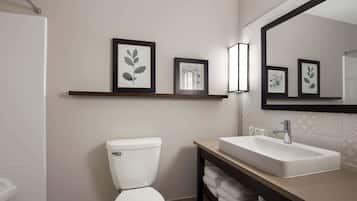 A modern bathroom with a toilet, a sink, and framed artwork on the wall.