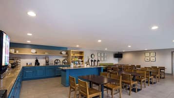 A restaurant with a blue counter, wooden tables, and chairs.