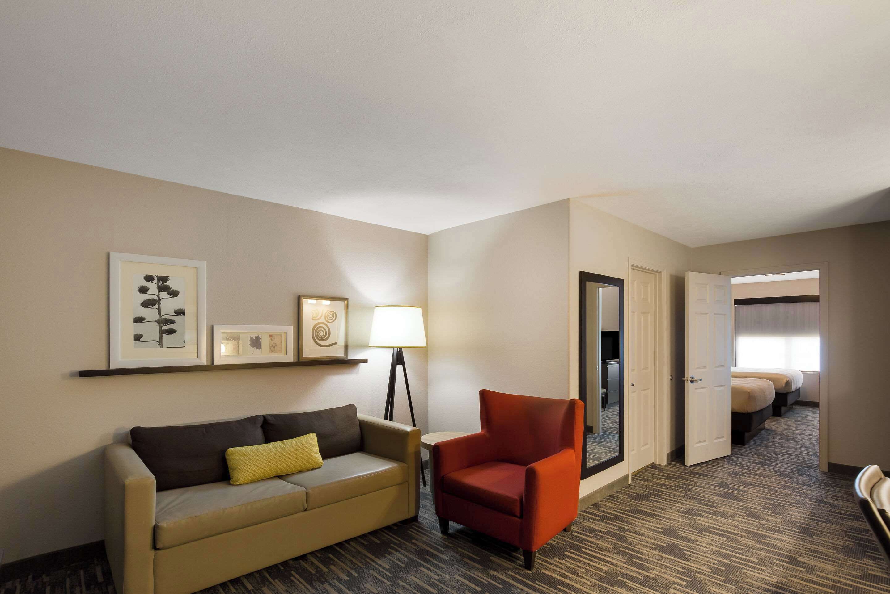 Una habitación de hotel con sofá, sillón, lámpara y cama.