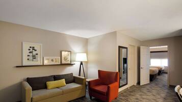 Una habitación de hotel con sofá, sillón, lámpara y cama.