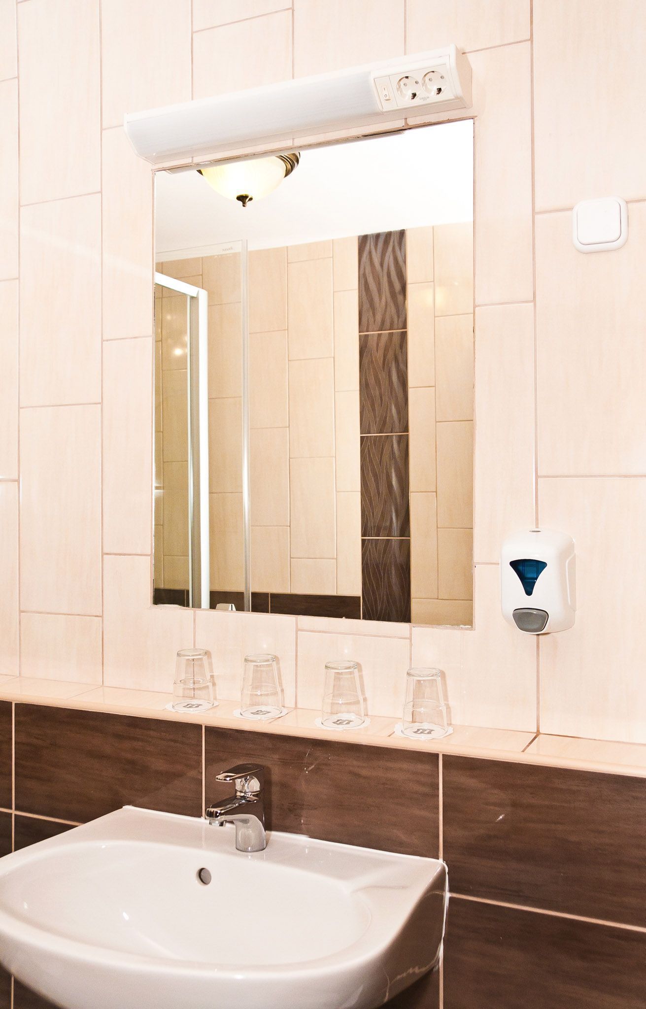 Une salle de bain avec un lavabo blanc, un miroir et un distributeur de savon.