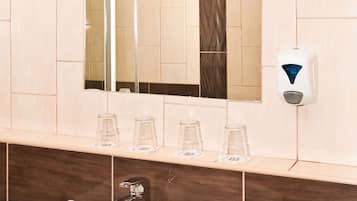 Une salle de bain avec un lavabo blanc, un miroir et un distributeur de savon.