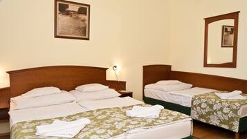Una habitación de hotel con dos camas individuales, una mesita de noche con lámpara y un cuadro en la pared.