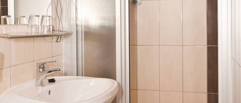 A bathroom with a sink, mirror, and glass-enclosed shower.