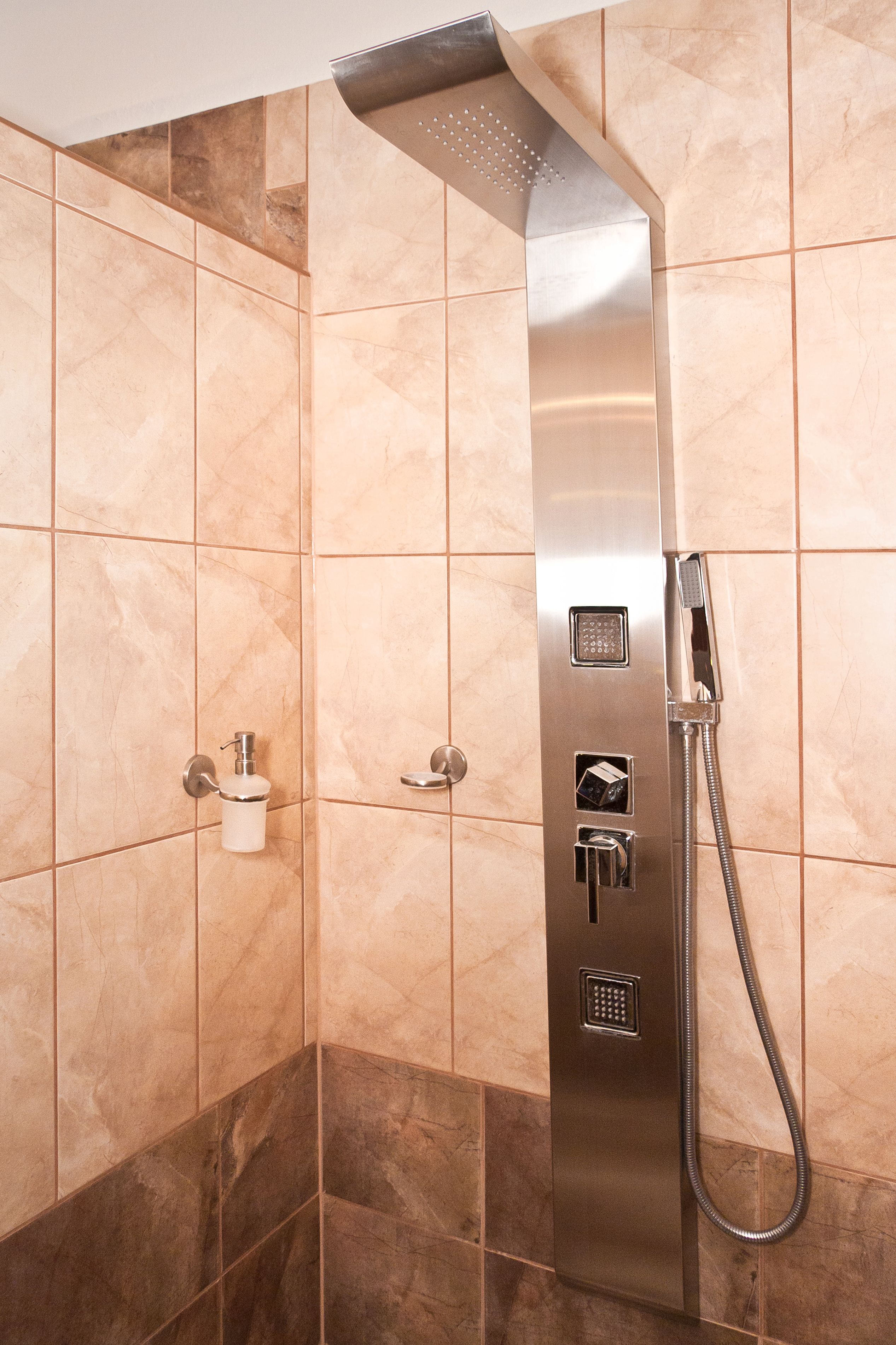 A modern shower with a handheld showerhead, a built-in soap dispenser, and a control panel.