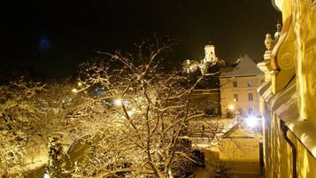 A snow-covered tree in front of a building with a tower.