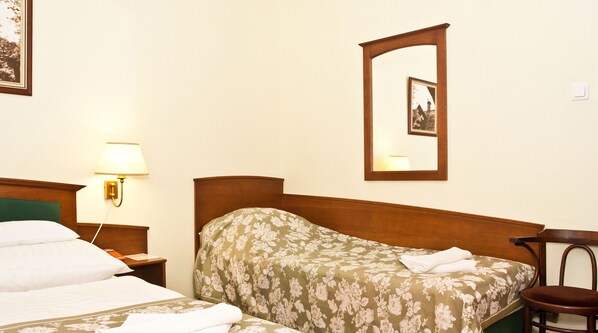 Une chambre d’hôtel avec un lit, une table de chevet avec une lampe, une chaise et un miroir fixé au mur.