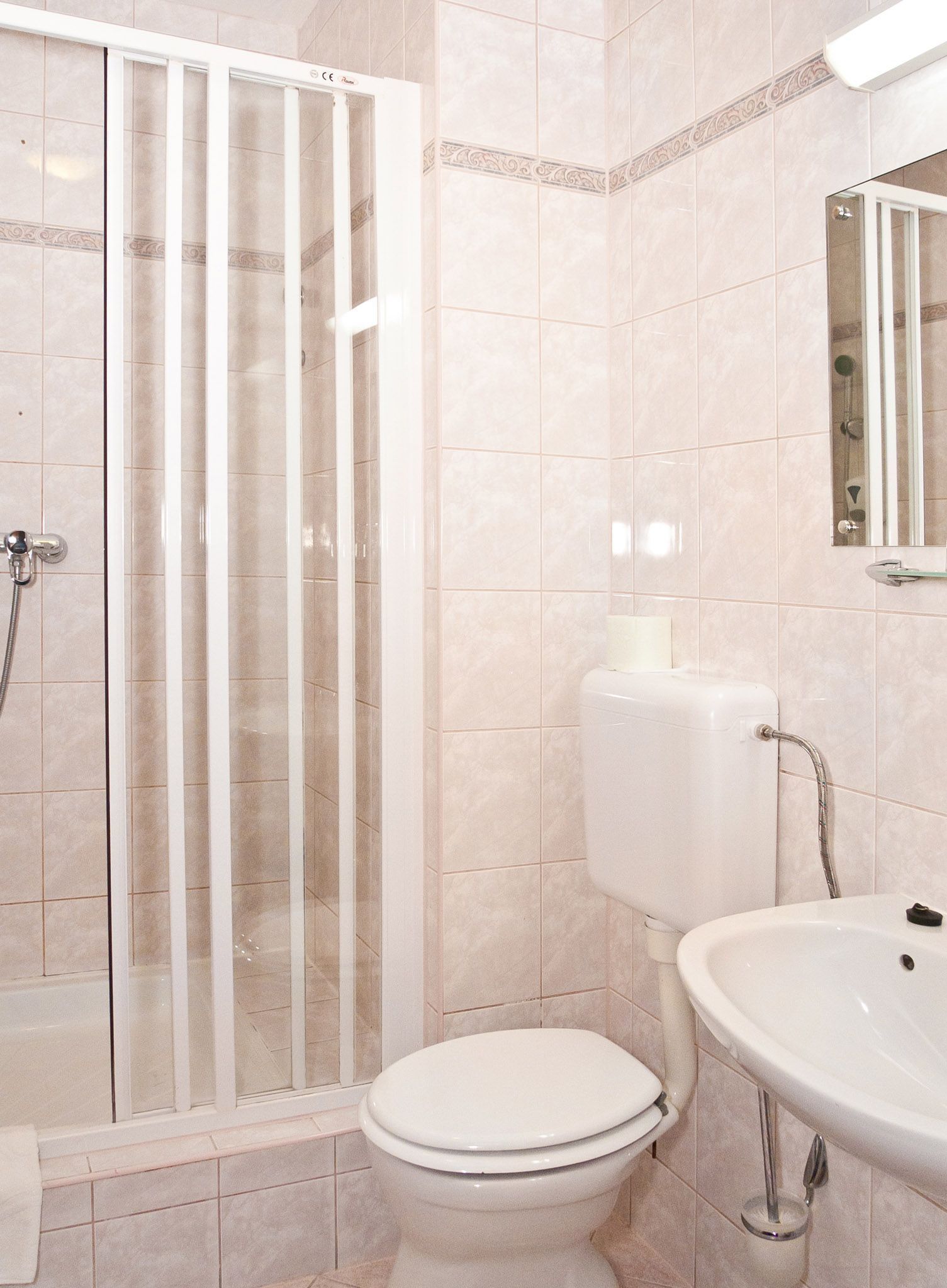 A bathroom with a shower enclosure, toilet, and sink.