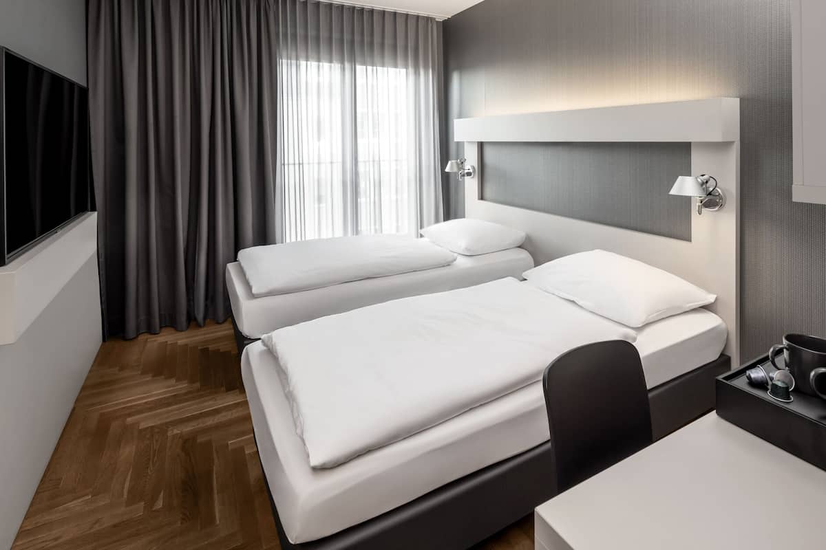 Una habitación de hotel con dos camas, un escritorio y un televisor.