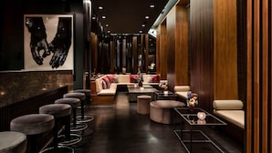 A modern lounge area with a sofa set, round bar stools, and a coffee table. - Hotel AMANO Rooms & Apartments (Berlin)