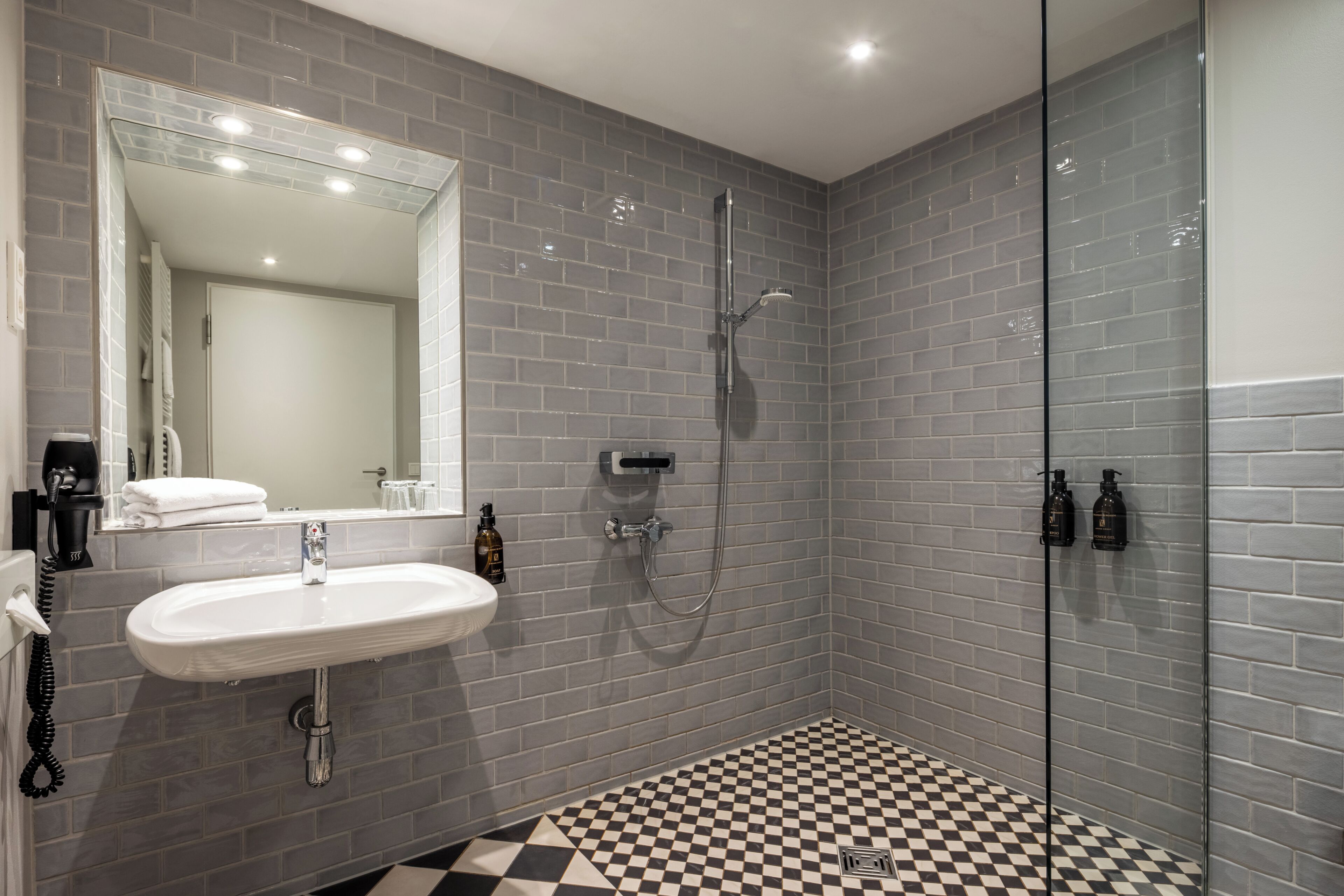 A modern bathroom with a checkered floor, a sink, a mirror, and a shower.