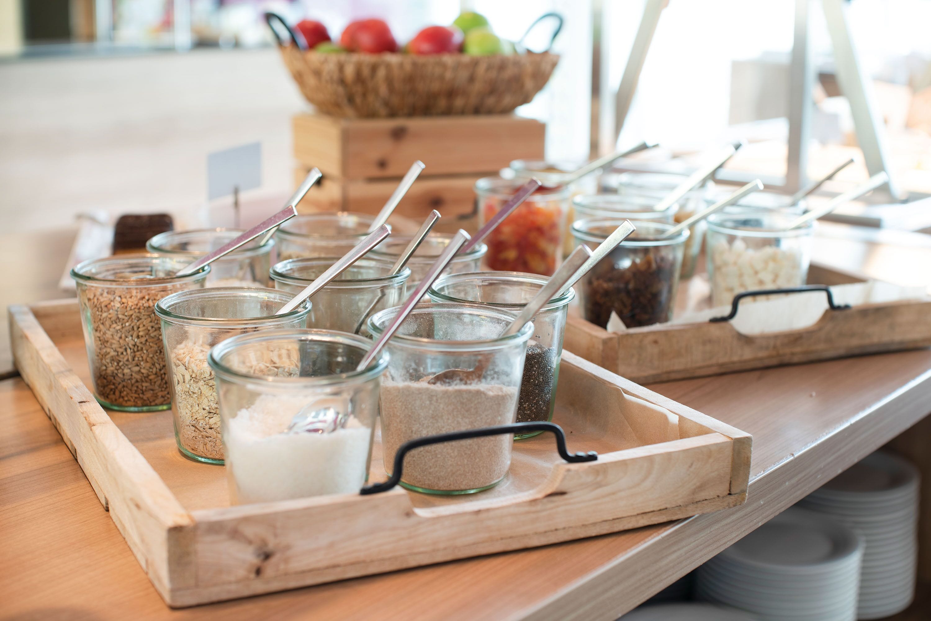 A wooden tray with glass jars containing various food items and utensils.
