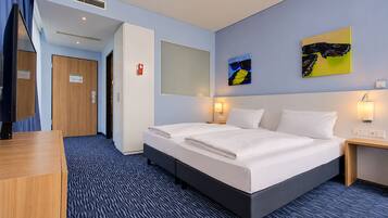 A hotel room with a bed, bedside tables, a desk, and a mirror.