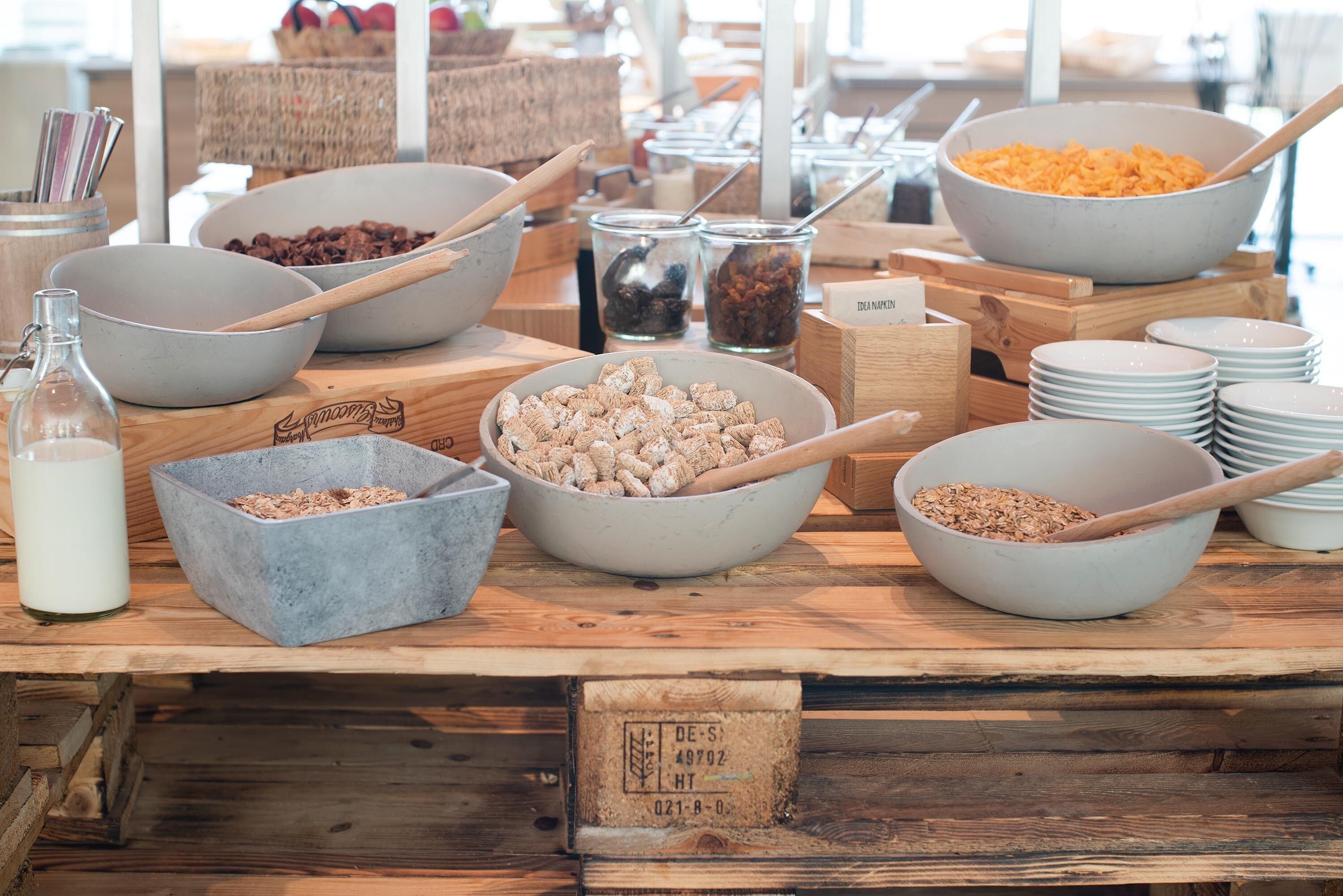 Een ontbijtbuffet met diverse soorten eten en bestek op een houten tafel.