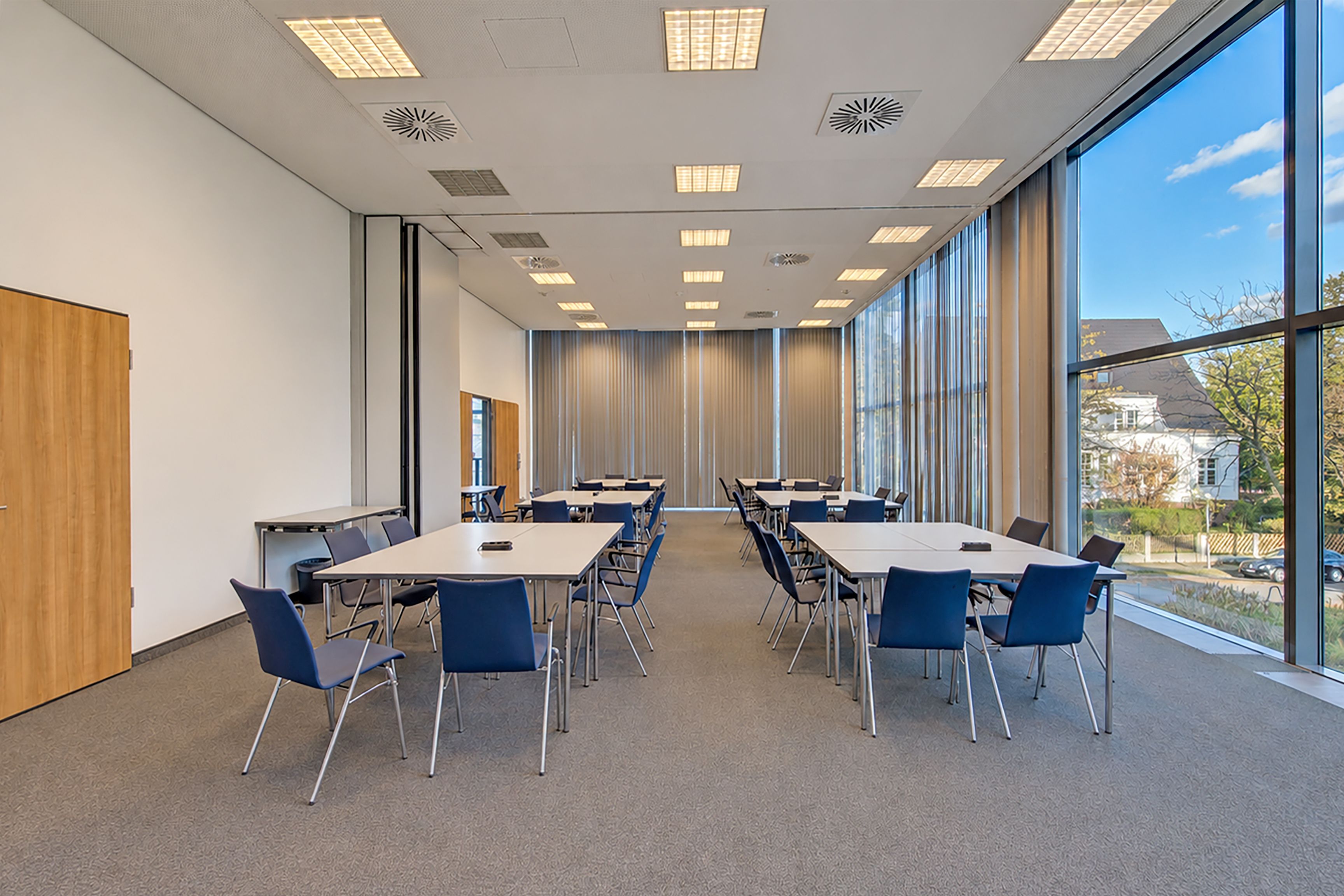 A conference room with a long table, chairs, and large windows.
