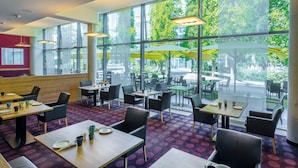 A modern restaurant with large windows, indoor seating, and a view of the outdoors. - Seminaris CampusHotel Berlin (Berlin)