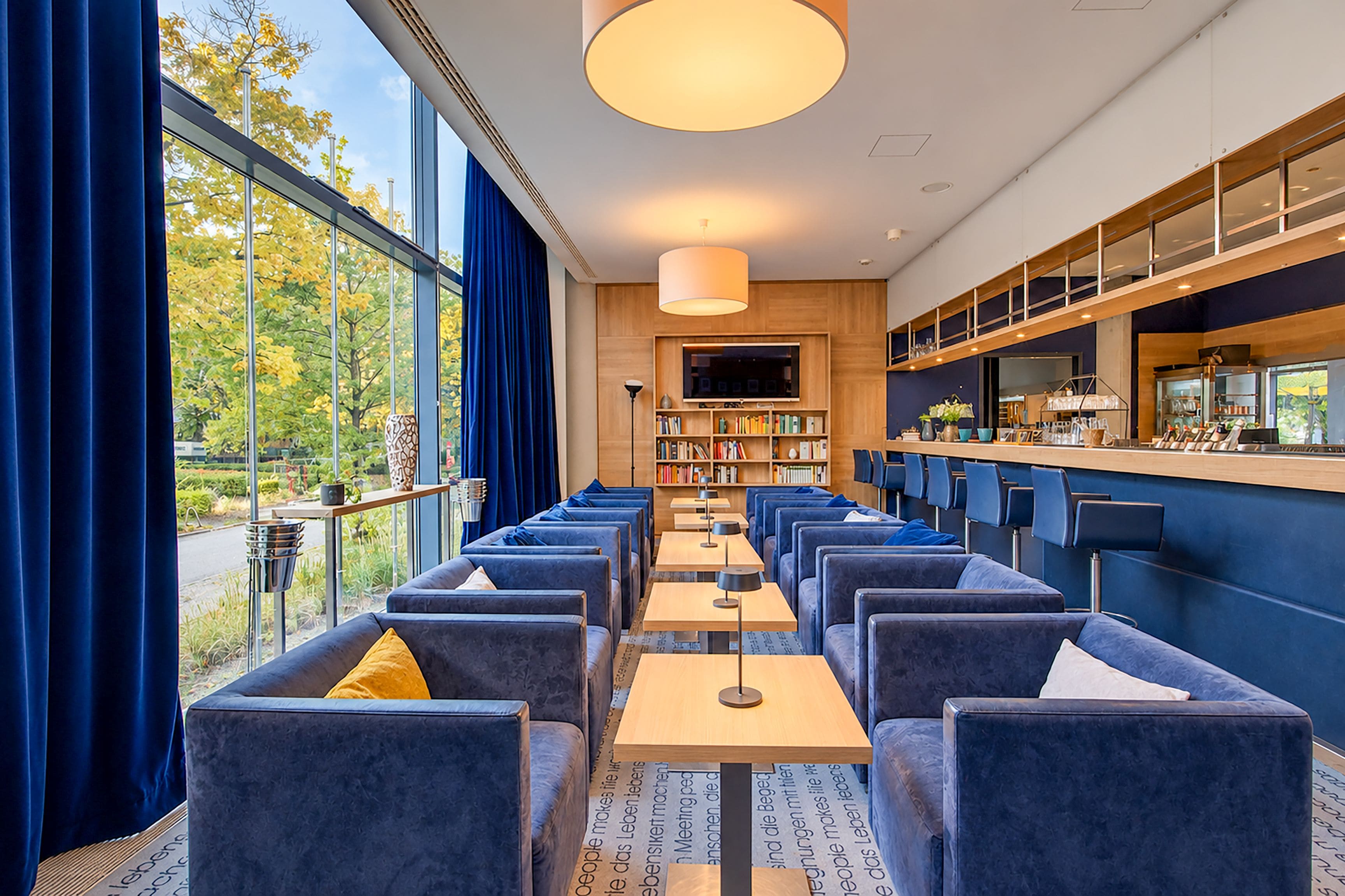 Een moderne barruimte met zitplaatsen, een televisie en een boekenplank.