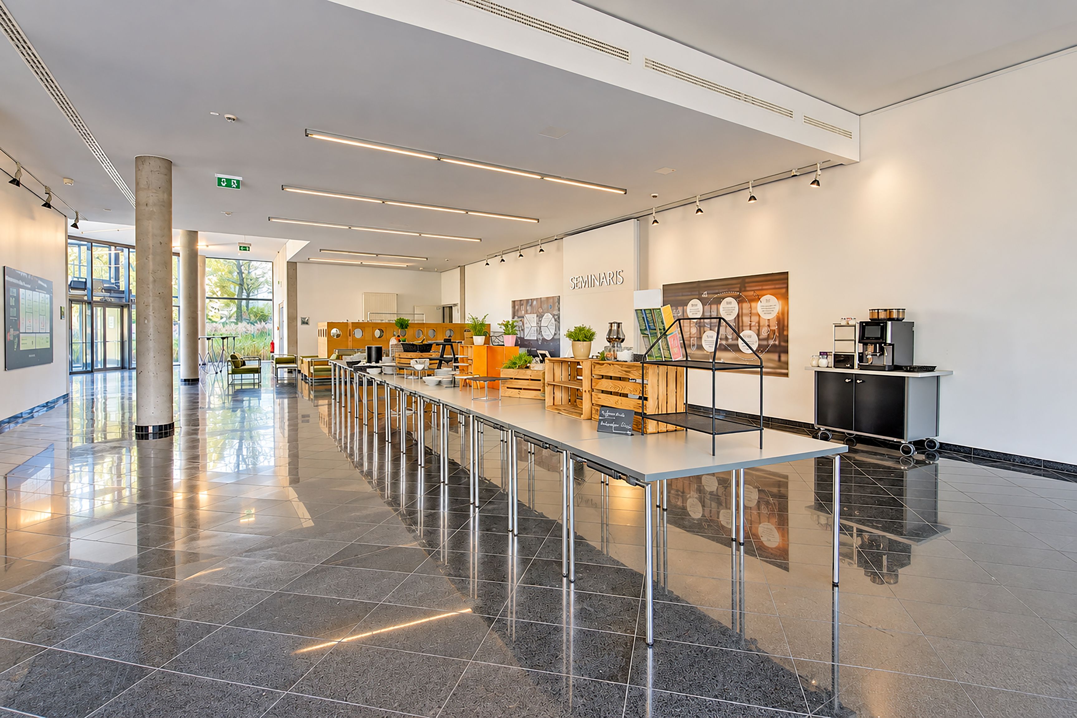 Eine moderne, geräumige Lobby mit einer langen Rezeption, einer Sitzecke und einer Wandanzeige.