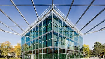 A modern glass building with a steel framework, large windows, and a flat roof.