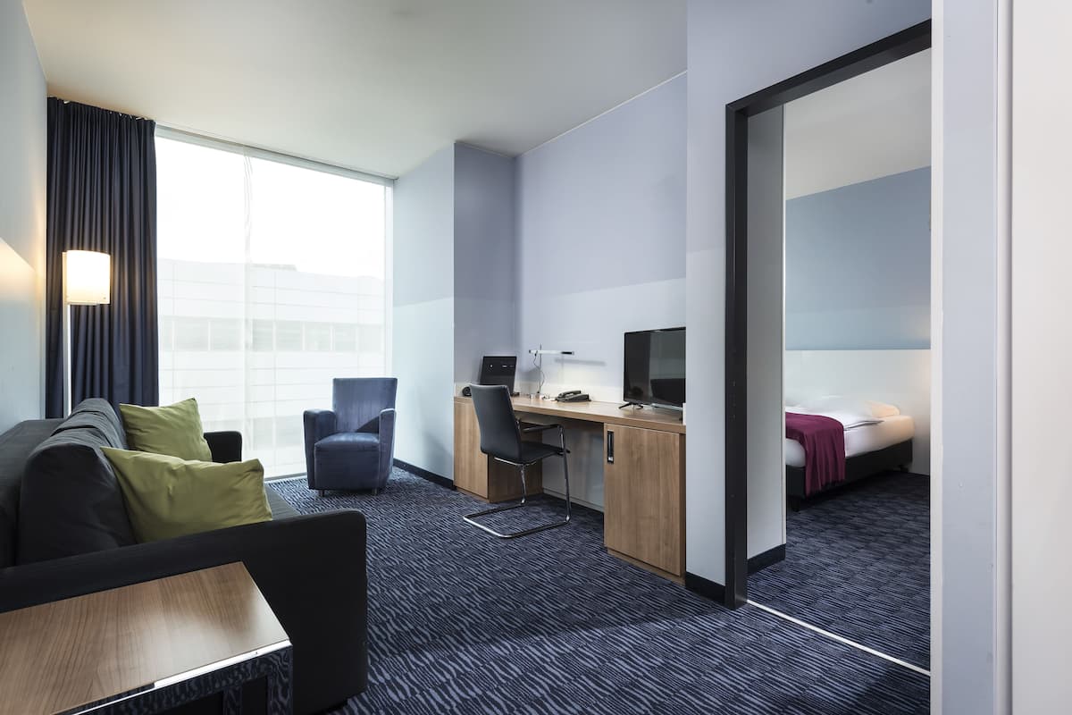 A modern hotel room with a sofa, desk, and computer.