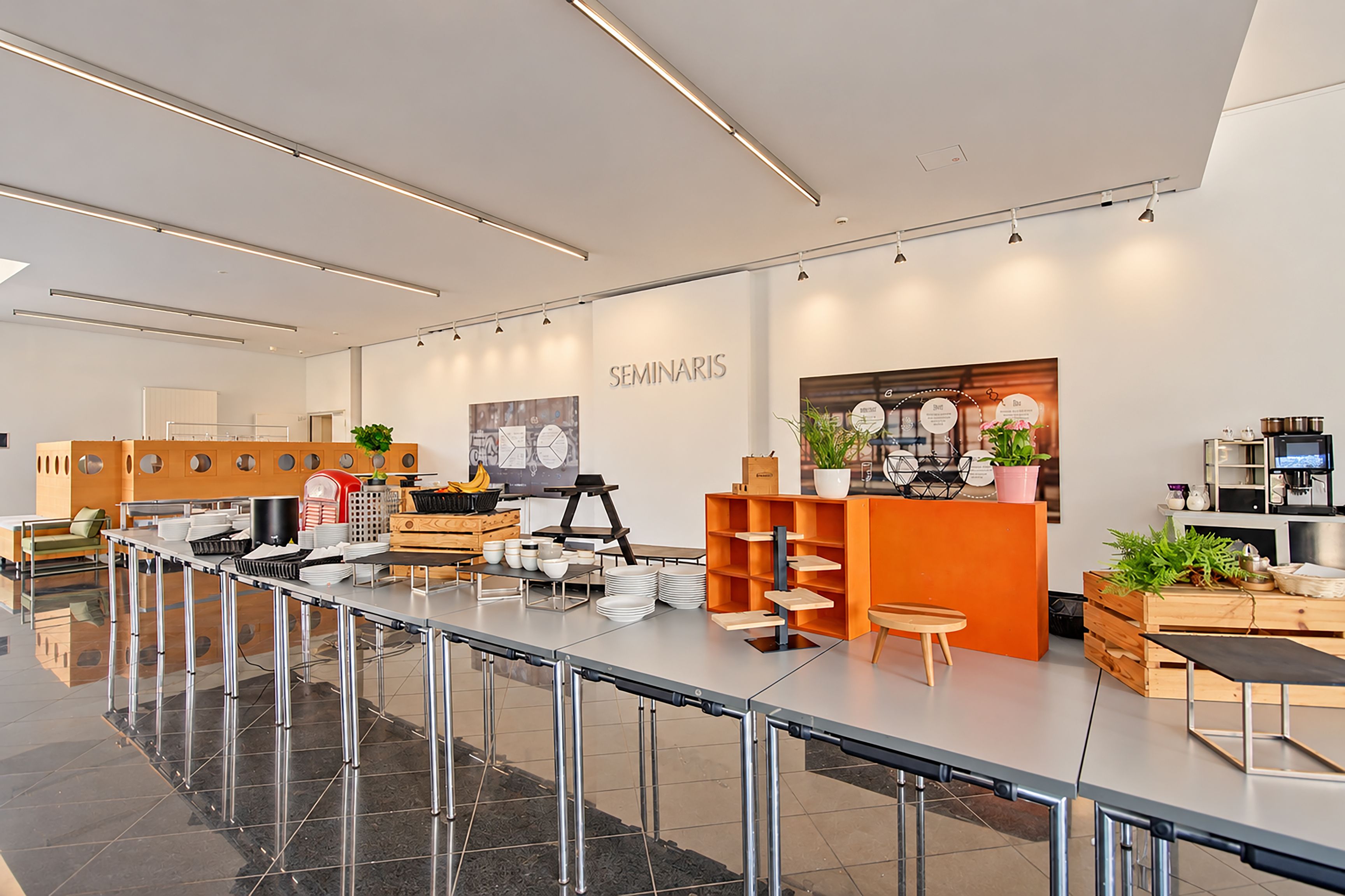 Una cafetería moderna y luminosa, con una barra larga, zona de estar y un menú exhibido en la pared.