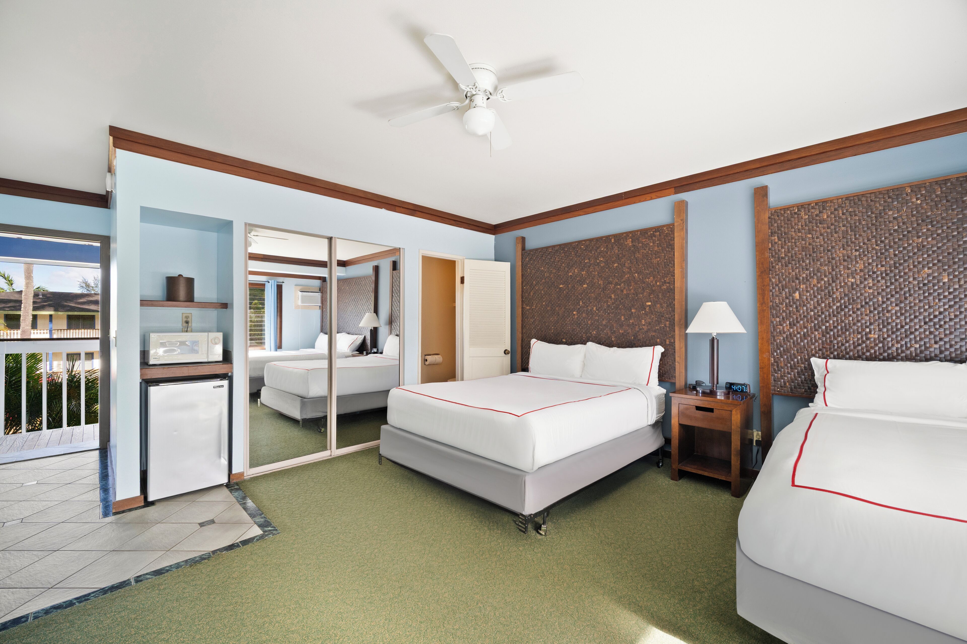 A hotel room with a bed, a desk, a chair, a microwave, and a refrigerator.