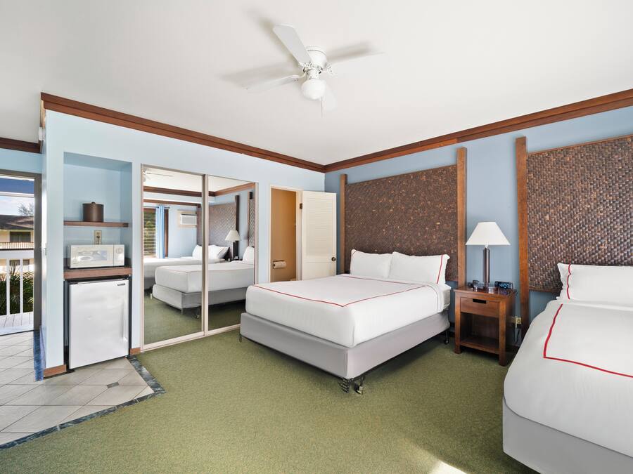 A hotel room with a bed, a desk, a chair, a microwave, and a refrigerator.