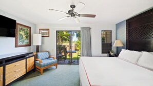 Une chambre d’hôtel comprenant un lit, un bureau avec des tiroirs, une chaise, un ventilateur de plafond et une vue sur l’extérieur.
