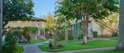 A landscaped courtyard with pathways, trees, and a building with a covered walkway.