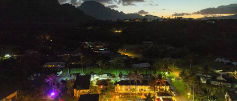 Un resort con piscina, senderos iluminados y vista a las montañas al atardecer.