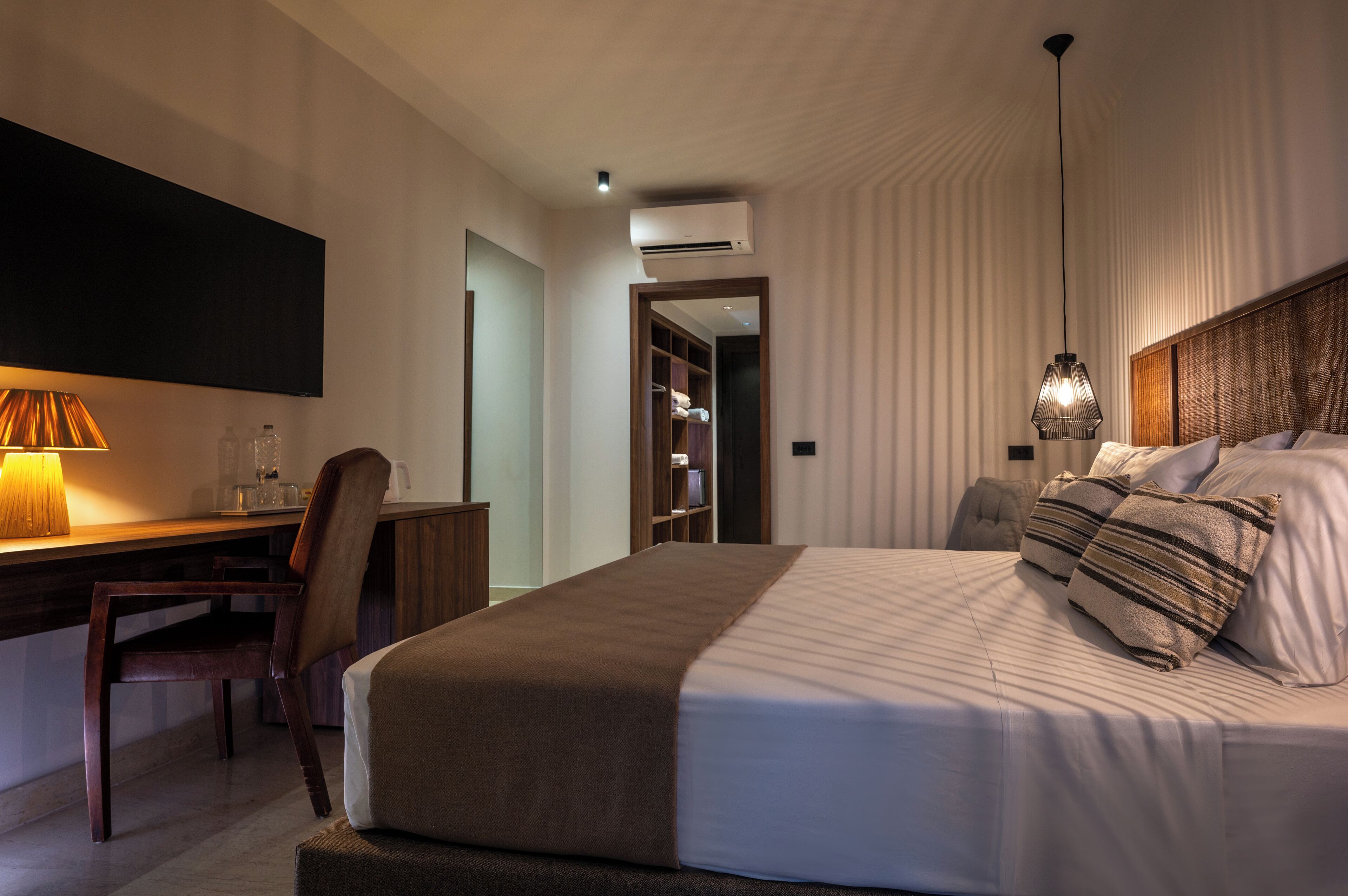 A hotel room with a bed, desk, chair, and a wardrobe.