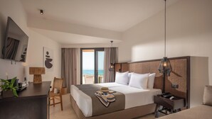 Habitación de hotel con cama, escritorio, silla y vista a la playa.