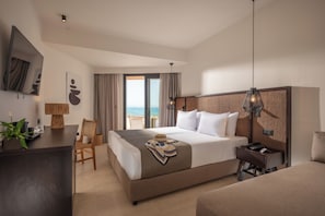 A hotel room with a bed, desk, chair, and a view of the beach. - Oya Beach Resort – All Inclusive (Hersonissos)
