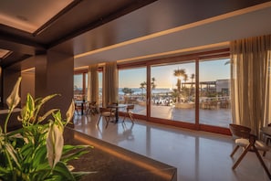 A modern hotel lobby with a large glass wall, a reception desk, and seating area. - Oya Beach Resort – All Inclusive (Hersonissos)