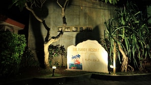 A sign for Balisandy Resort with palm trees and a beach scene. - Balisandy Resort (Kuta)