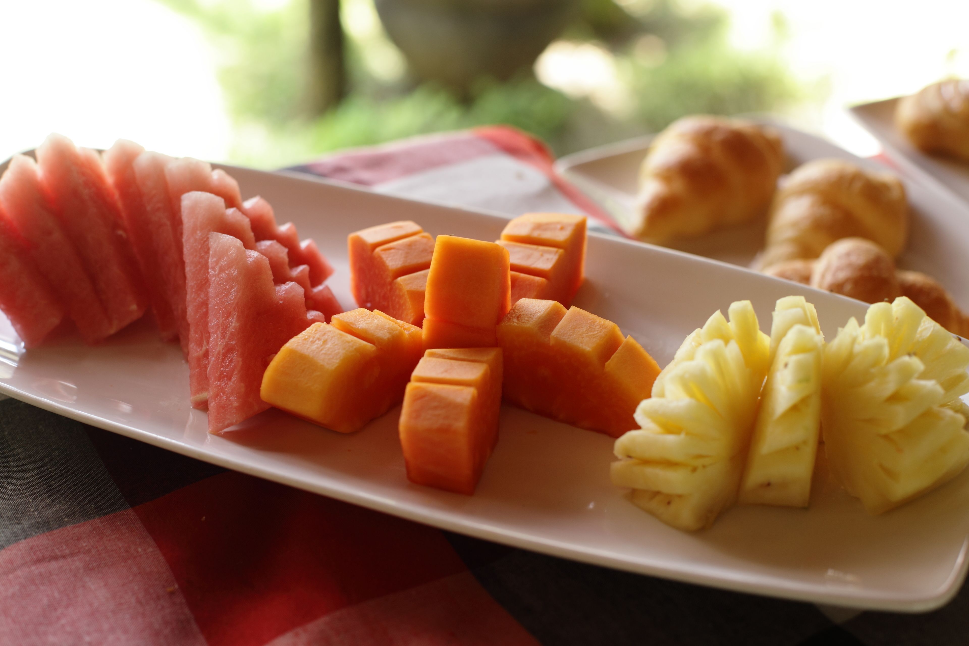 Un plato con mango, melón y piña en rodajas, dispuesto sobre un plato blanco.