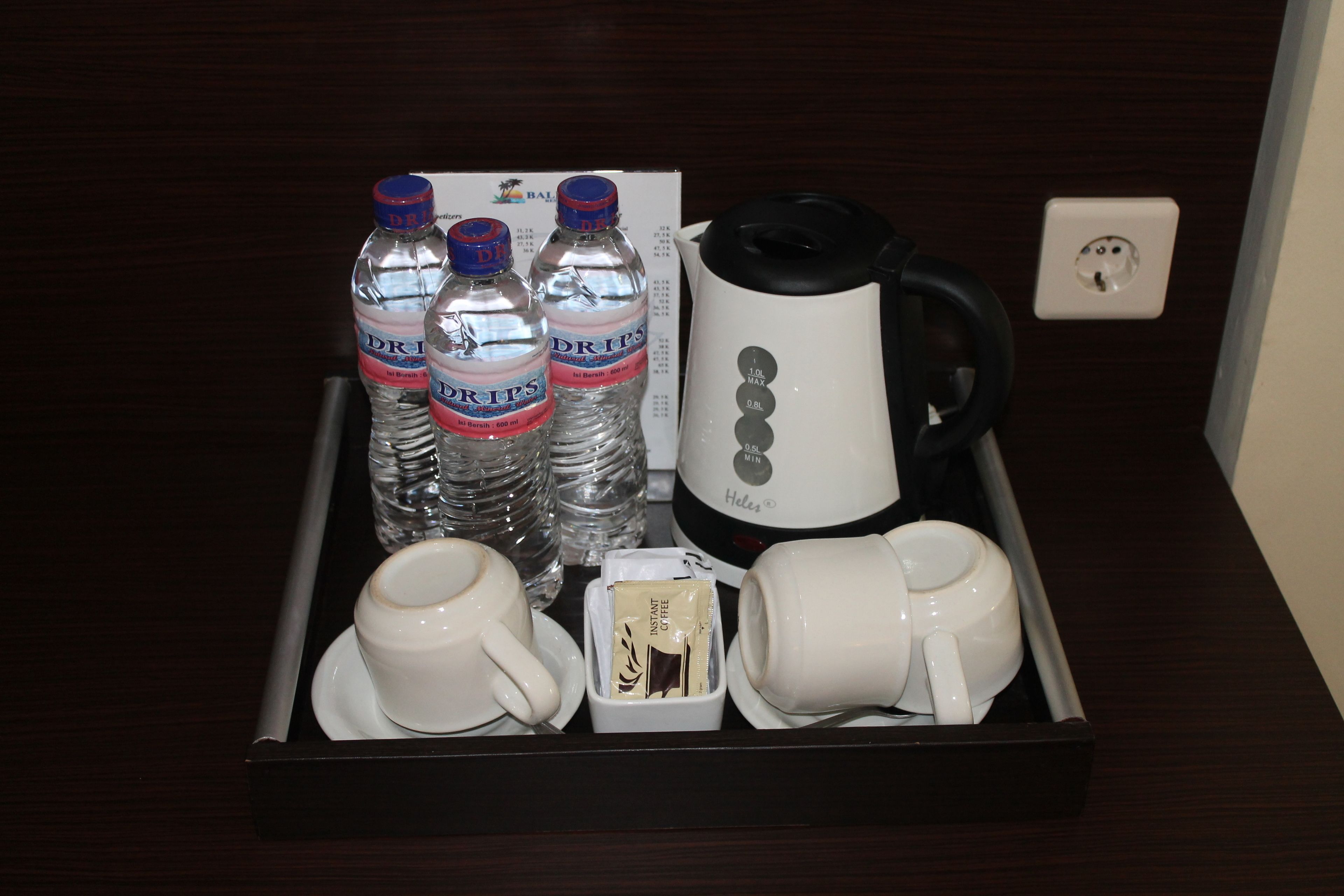 A tray with water bottles, a coffee maker, and cups.
