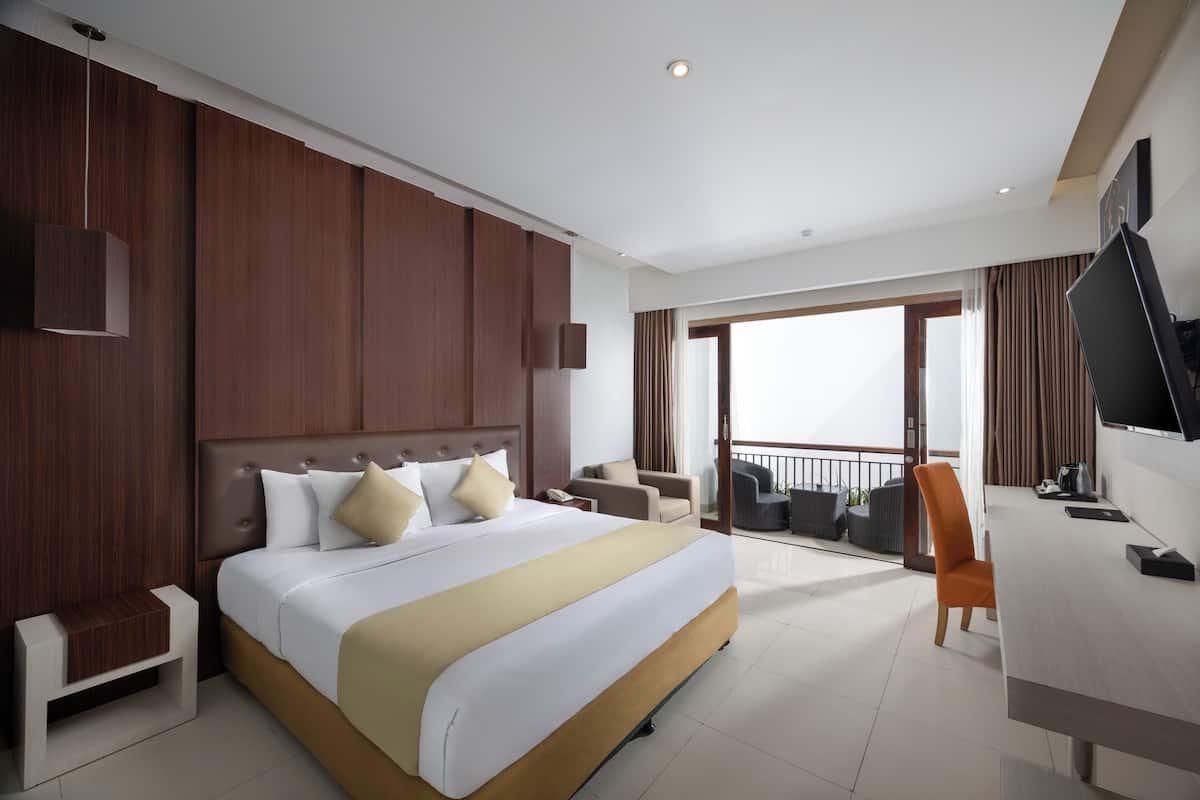 A modern hotel room with a large bed, a desk, a chair, and a TV.
