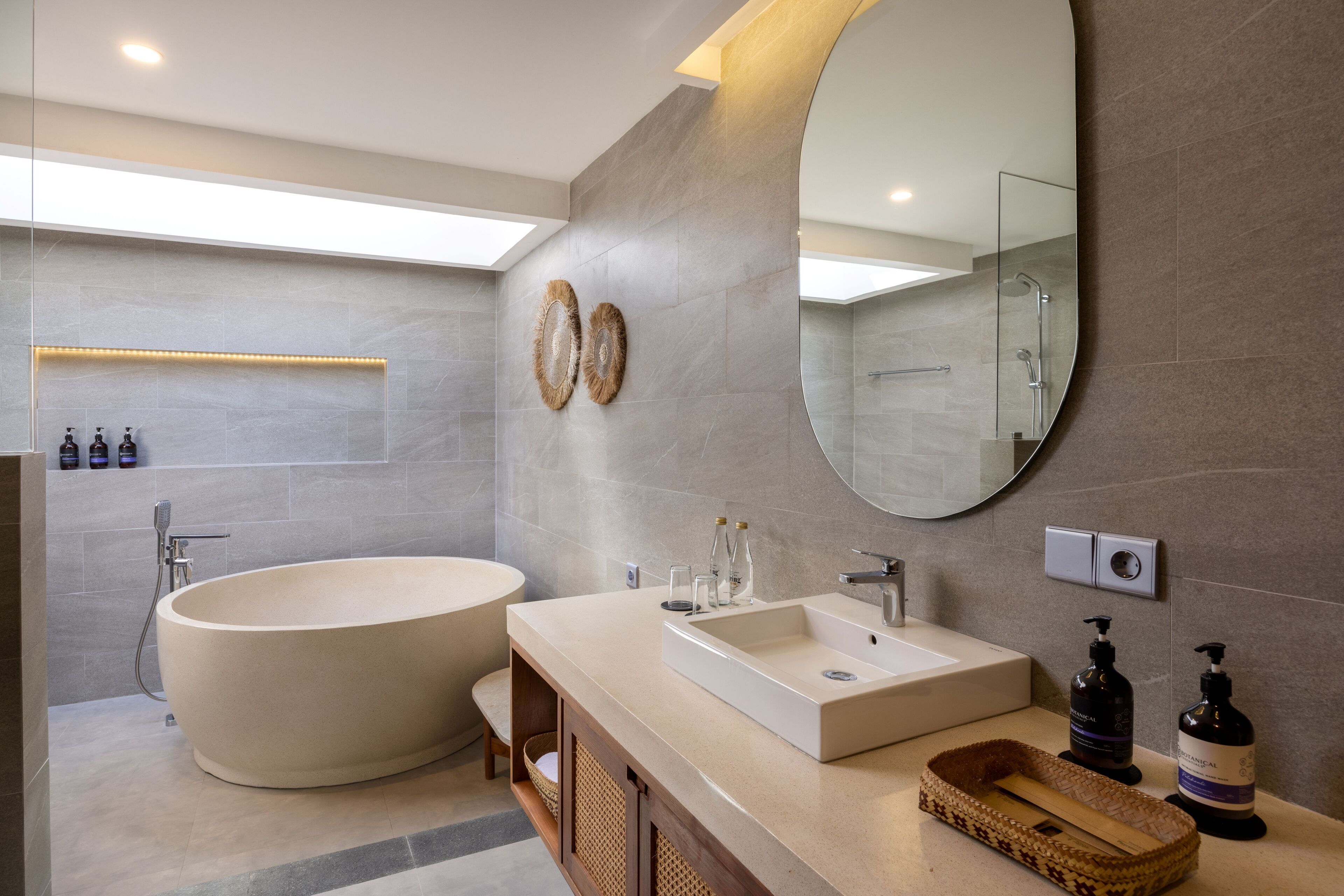 Ein modernes Badezimmer mit freistehender Badewanne, einem Waschtisch mit großem Spiegel und einer Duschkabine.