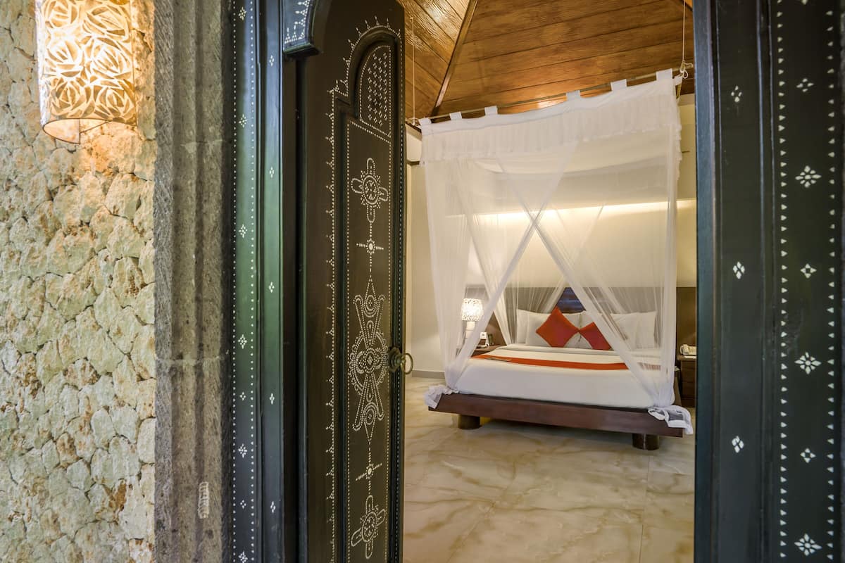A room with a bed, a nightstand, and a wall-mounted lamp.