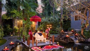 A serene garden setting with a dining area overlooking a pond, surrounded by lush greenery and a waterfall. - Tonys Villas & Resort (Keroboken Kelod)