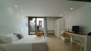 Habitación de hotel moderna con cama, escritorio, silla, televisor y vistas al exterior.
